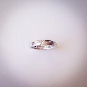 Platinum wedding band with flush-set diamonds, protea engraving on the outside and hummingbird engraving on the inside