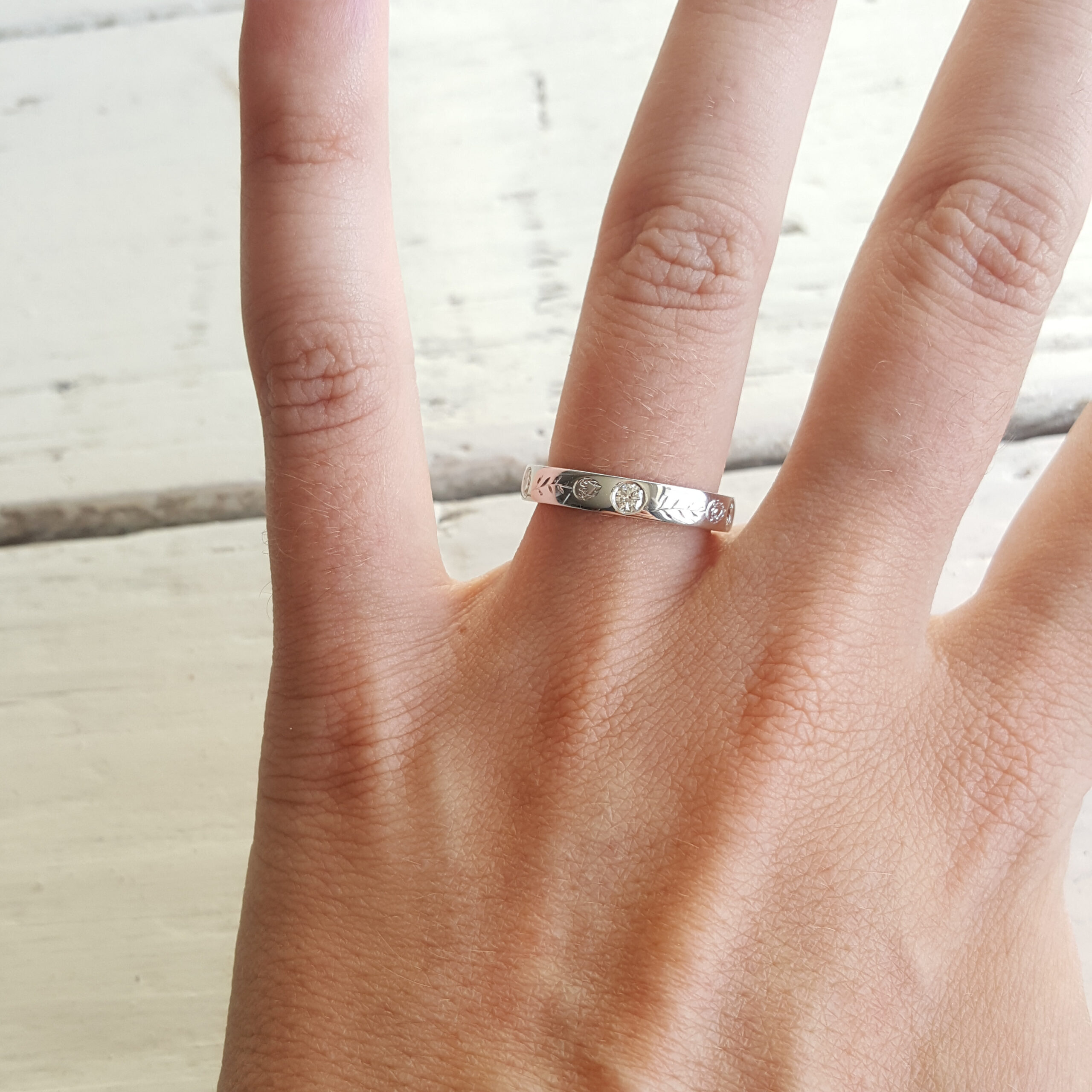Platinum wedding band with flush-set diamonds, protea engraving on the outside and hummingbird engraving on the inside