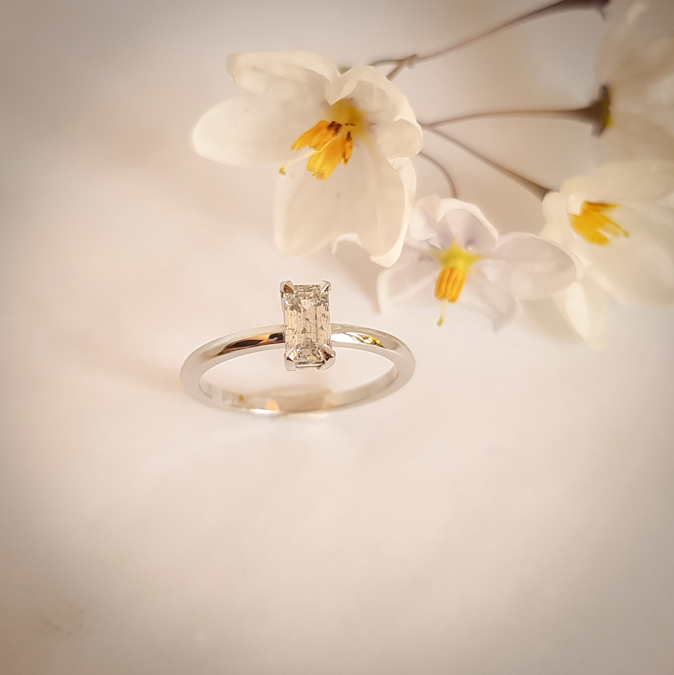 Platinum engagement ring with an emerald-cut salt and pepper diamond in a minimalist claw setting