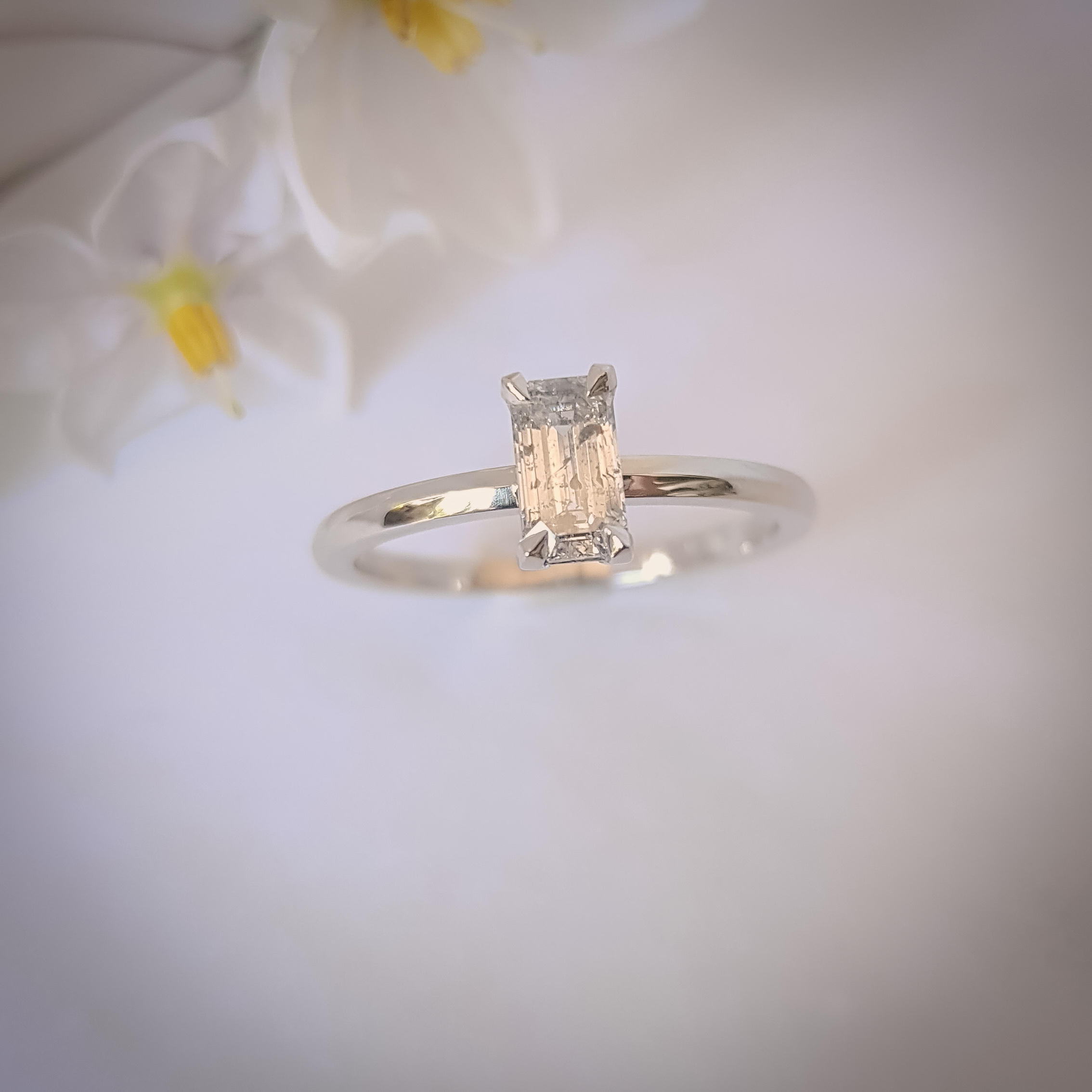 Platinum engagement ring with an emerald-cut salt and pepper diamond in a minimalist claw setting