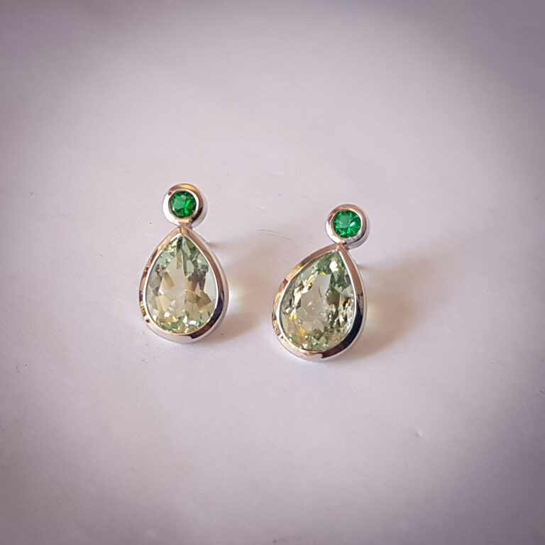 Silver drop earrings with pear-shaped prasiolite and round emerald gemstones in bezel settings