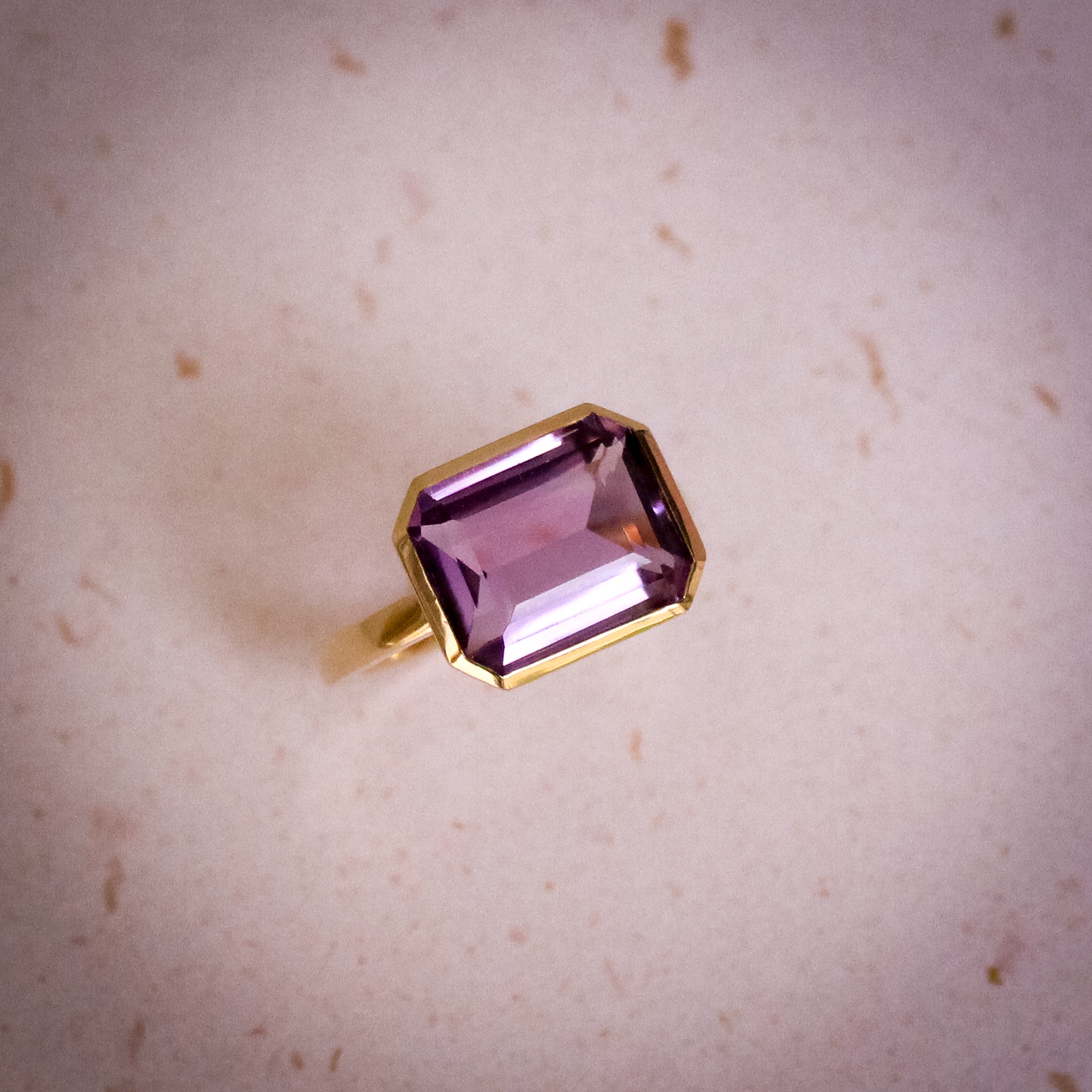 9k yellow gold ring set with a large emerald cut amethyst in a bezel setting