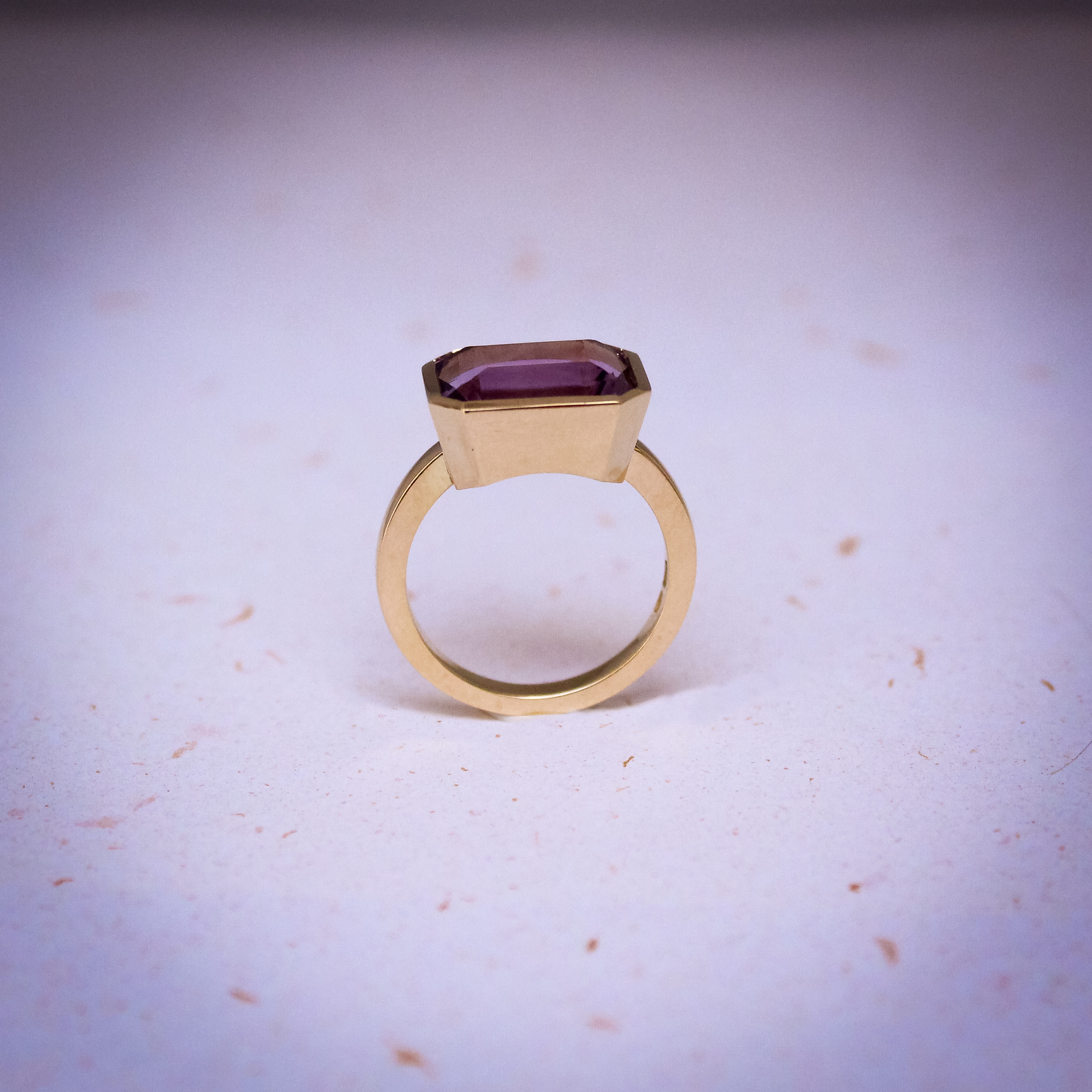 9k yellow gold ring set with a large emerald cut amethyst in a bezel setting