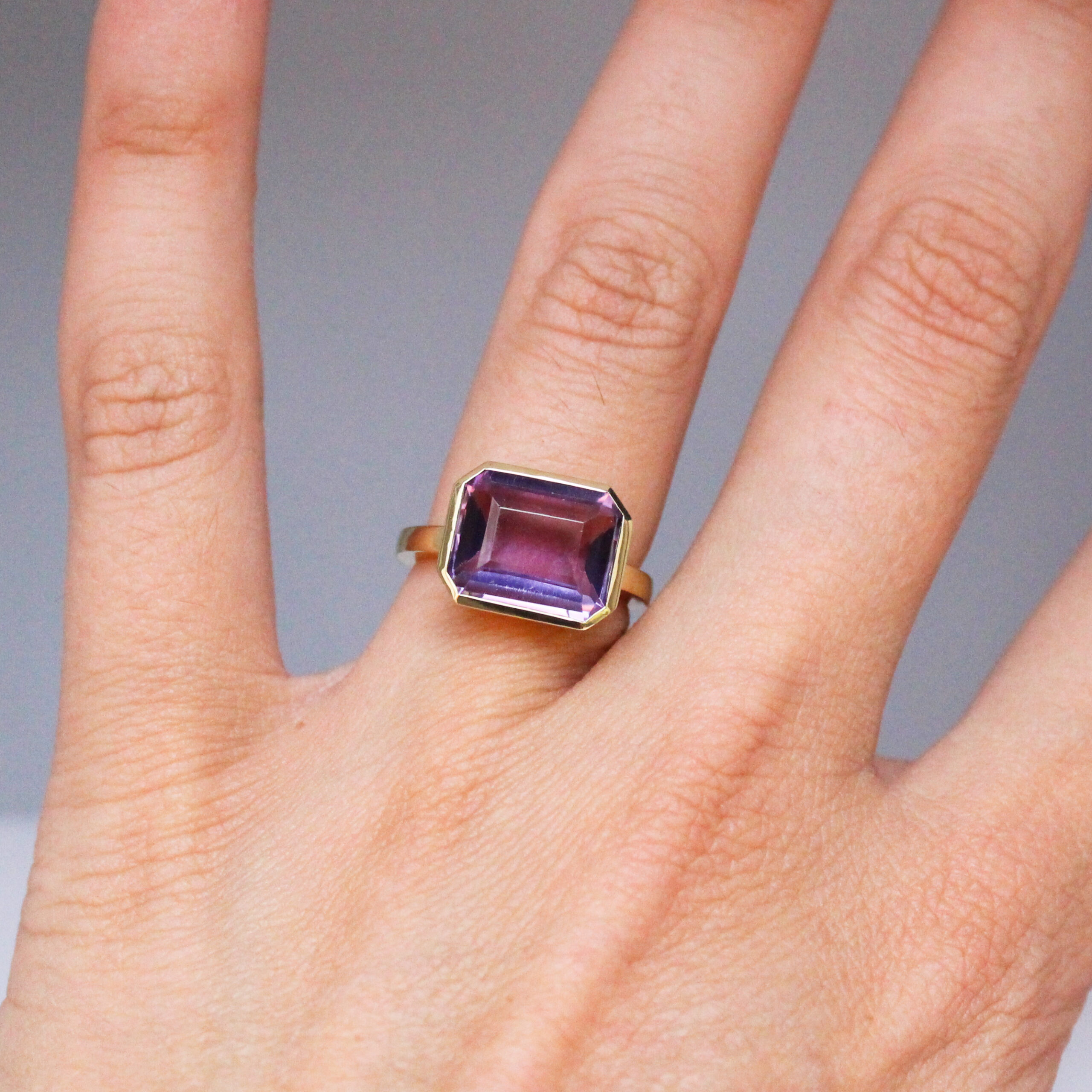 9k yellow gold ring set with a large emerald cut amethyst in a bezel setting