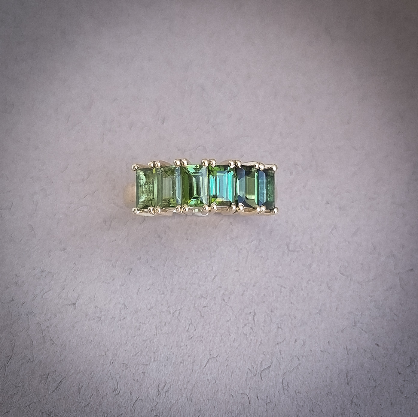 Emerald cut ombre green tourmaline half eternity ring set in yellow gold