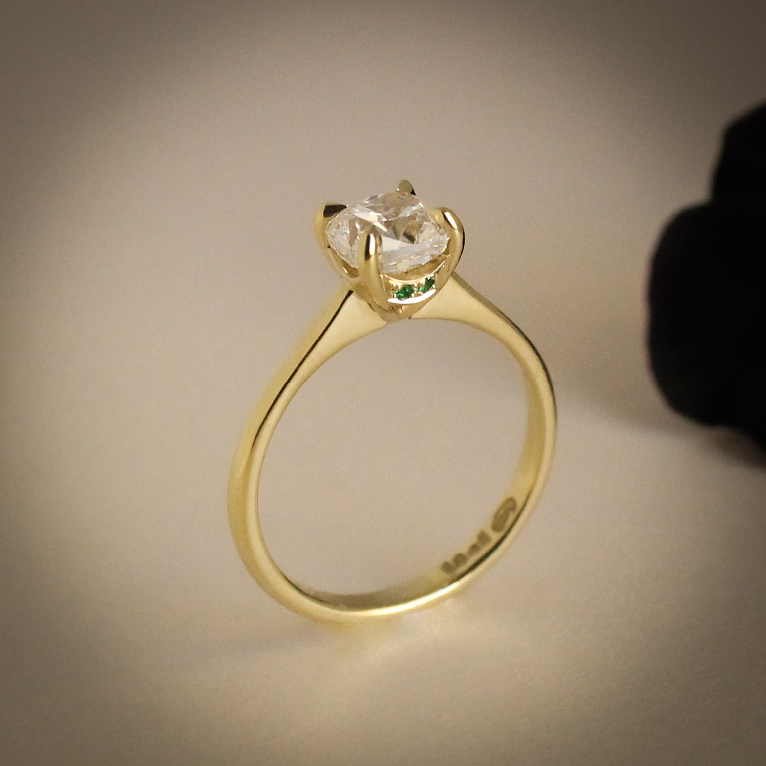 Cushion cut diamond engagement ring with hidden emerald stones in the setting