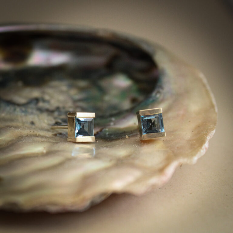 9k yellow gold stud earrings set with square cut aquamarine gemstones in a modern bezel-style setting