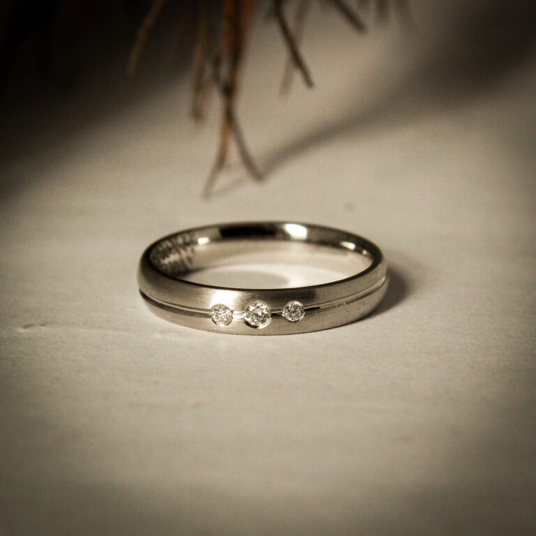 Platinum wedding band with three Swiss-set diamonds evenly spaced across the band