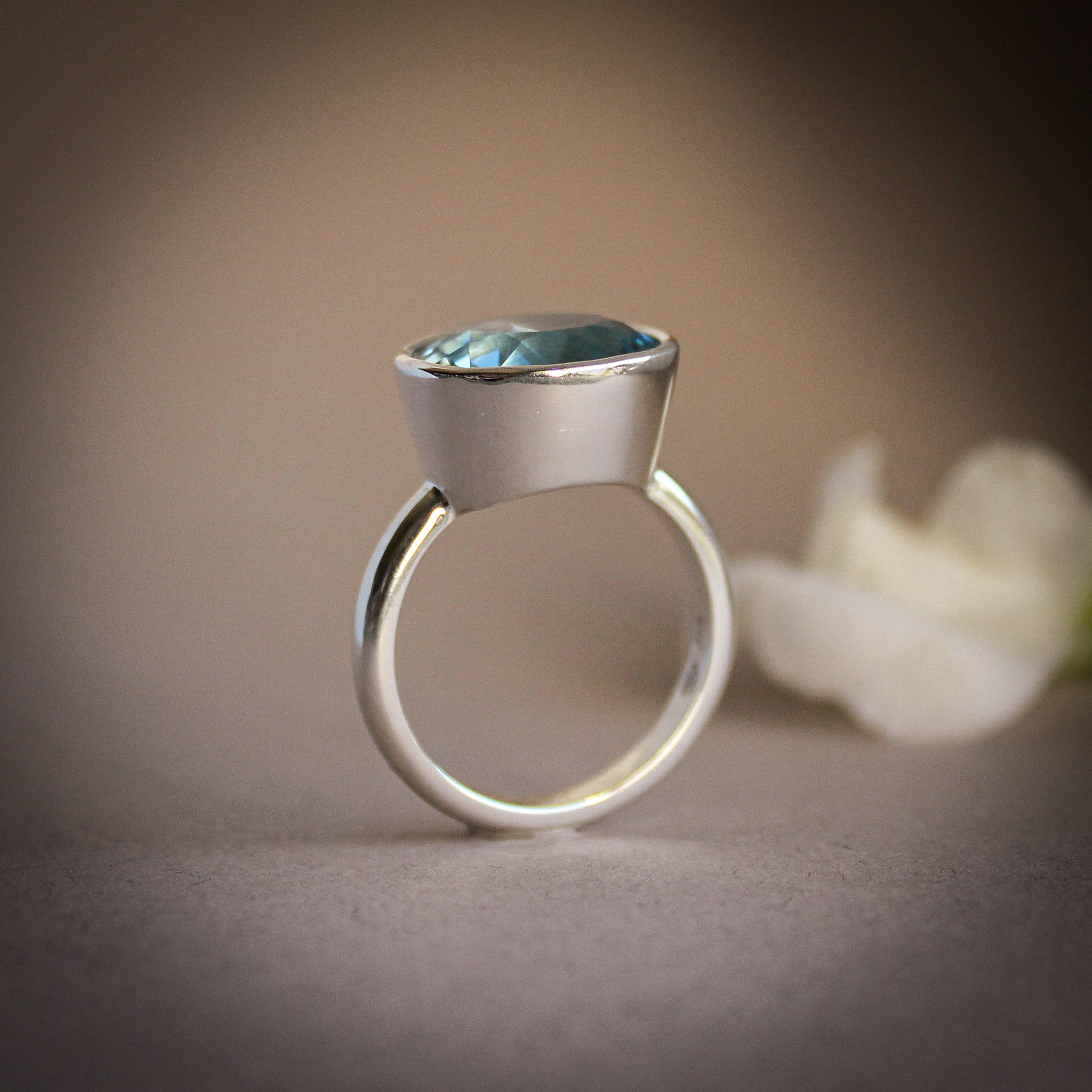 Round aquamarine gemstone set in a smooth silver bezel setting on a minimalist ring