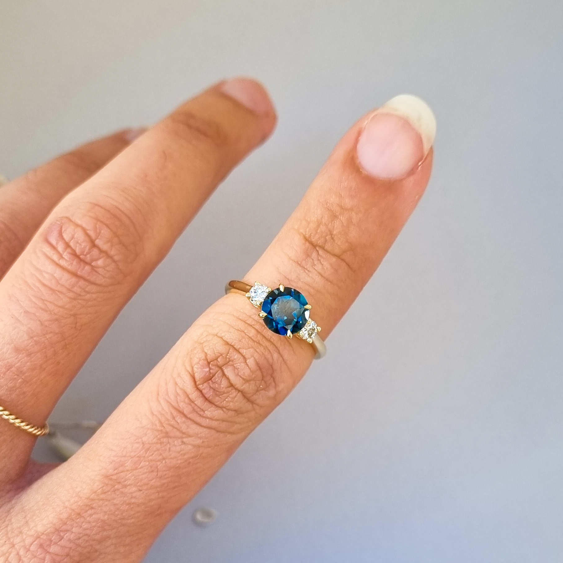 9k yellow gold engagement ring with round London blue topaz centre stone and two round diamonds