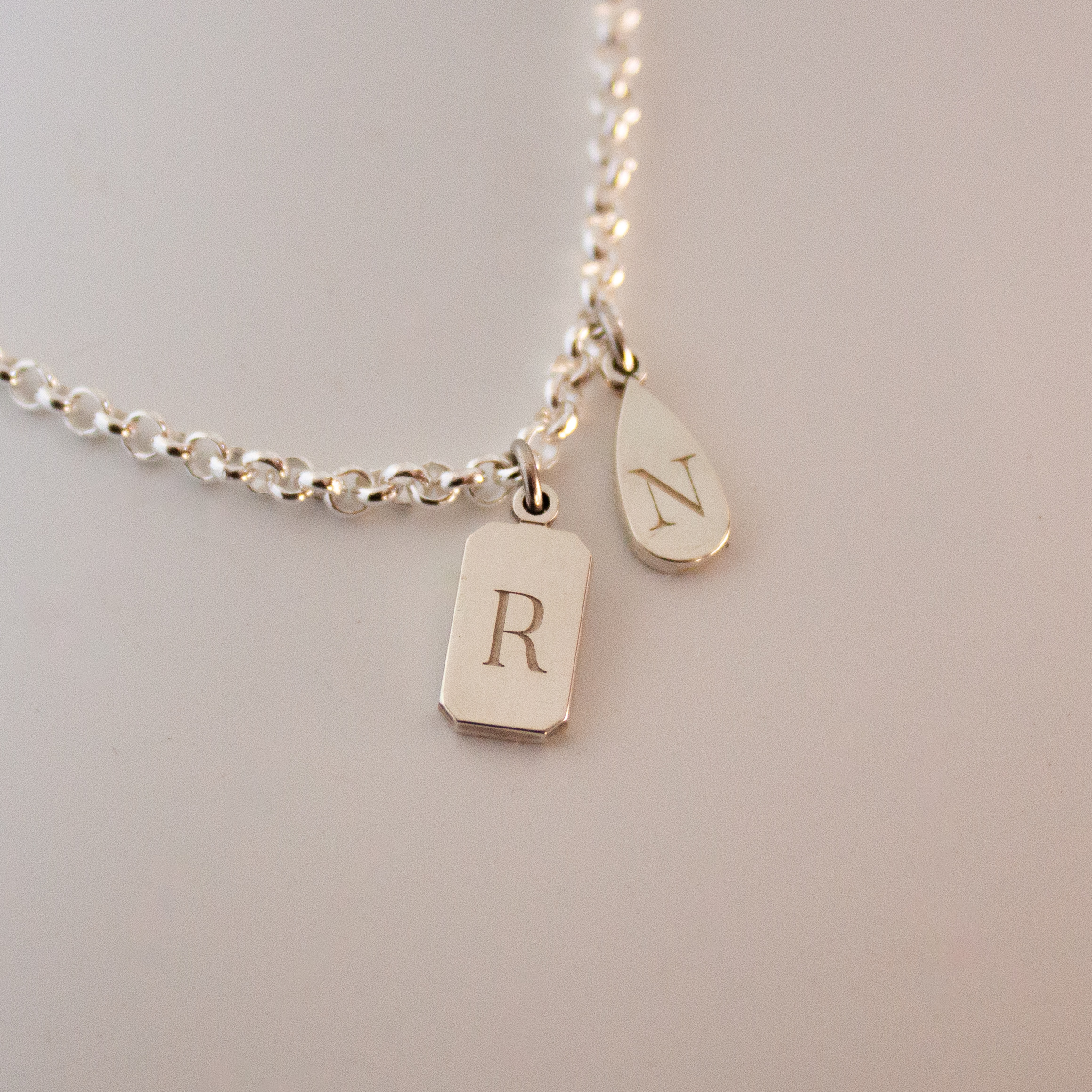 Personalised emerald shape initial tag necklace in gold with custom engraved initial and gemstone detail by Tyldesley Jewellers