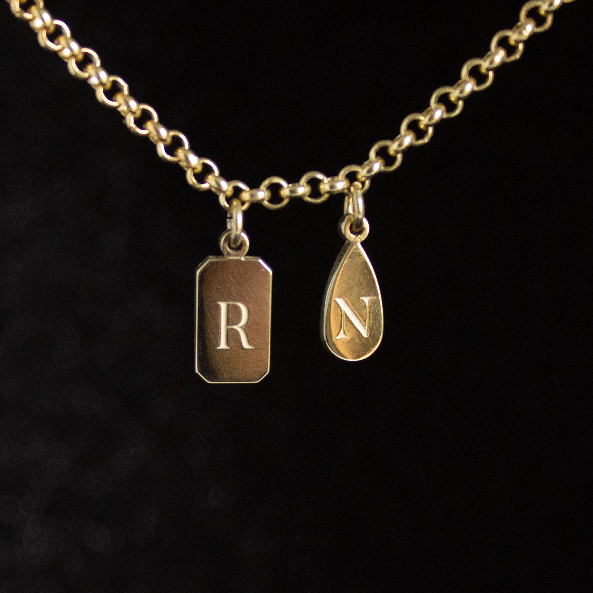 Personalised emerald shape initial tag necklace in gold with custom engraved initial and gemstone detail by Tyldesley Jewellers