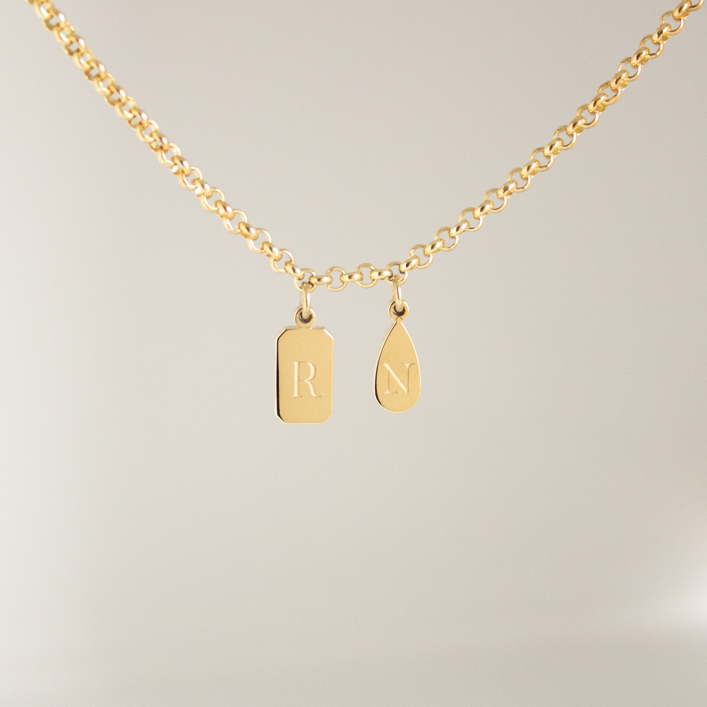 Personalised emerald shape initial tag necklace in gold with custom engraved initial and gemstone detail by Tyldesley Jewellers