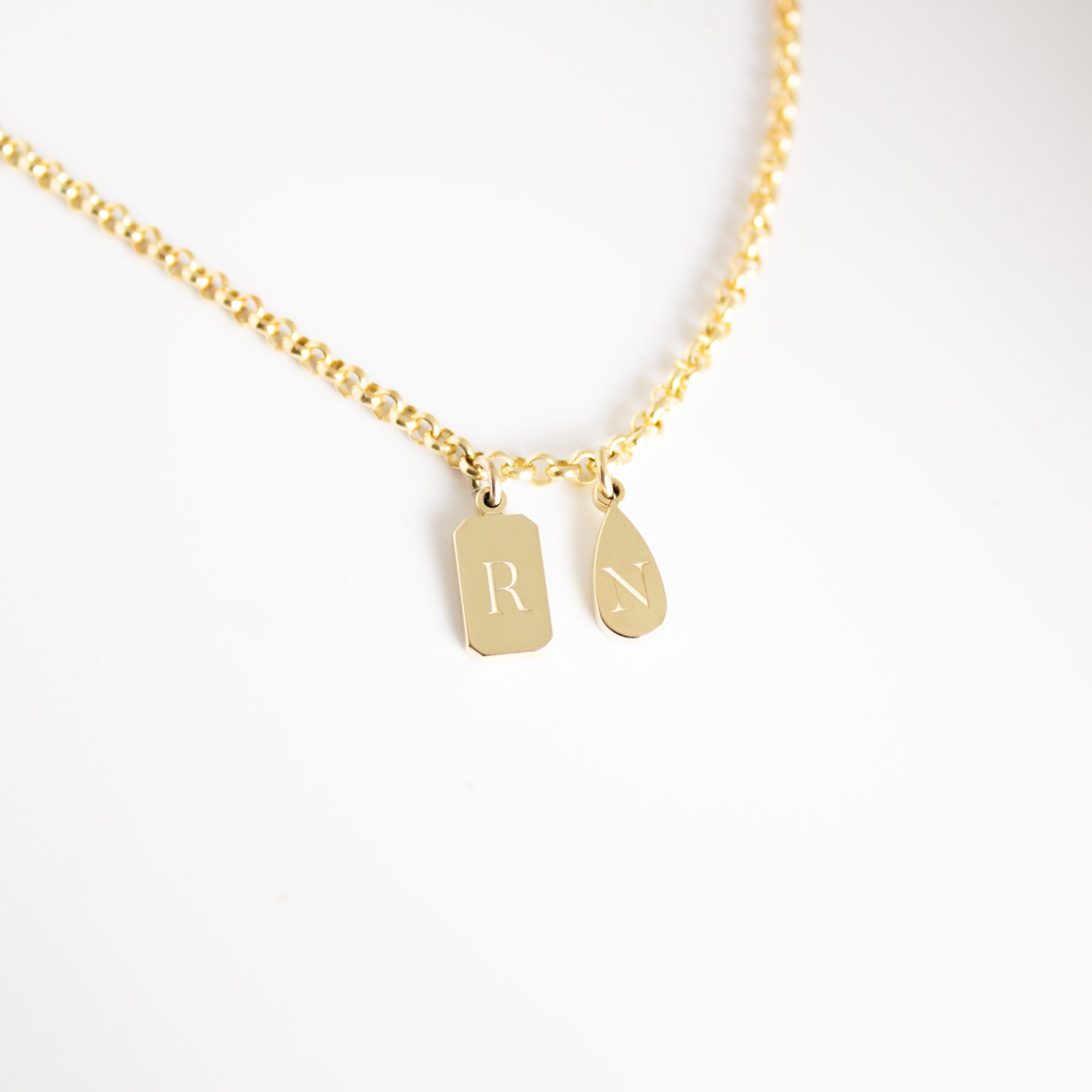 Personalised emerald shape initial tag necklace in gold with custom engraved initial and gemstone detail by Tyldesley Jewellers